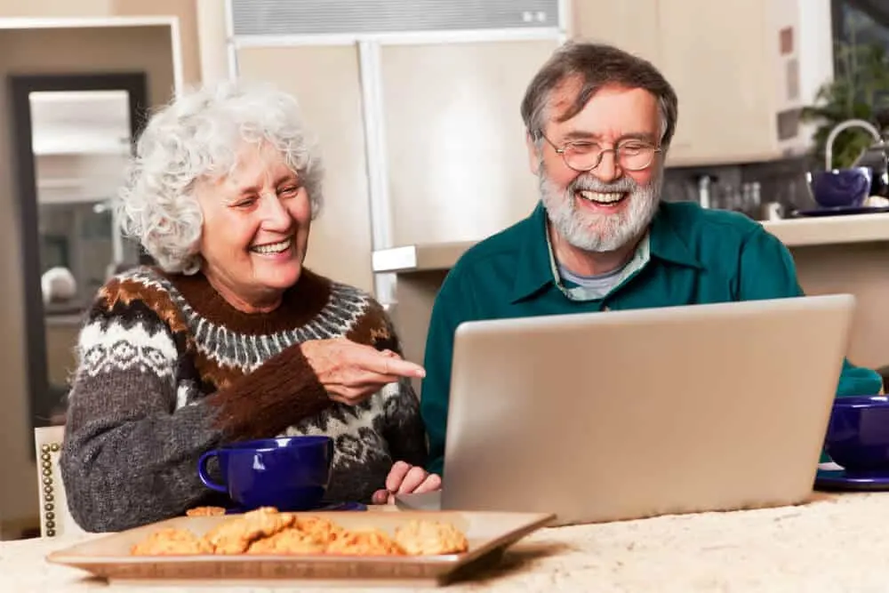 grandparents smiling happily at someone during a virtual zoom call on the computer