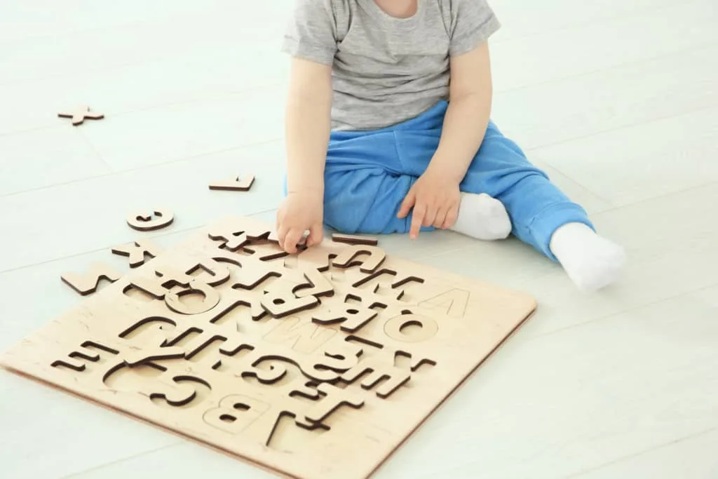 Boy plays with wooden letter puzzle