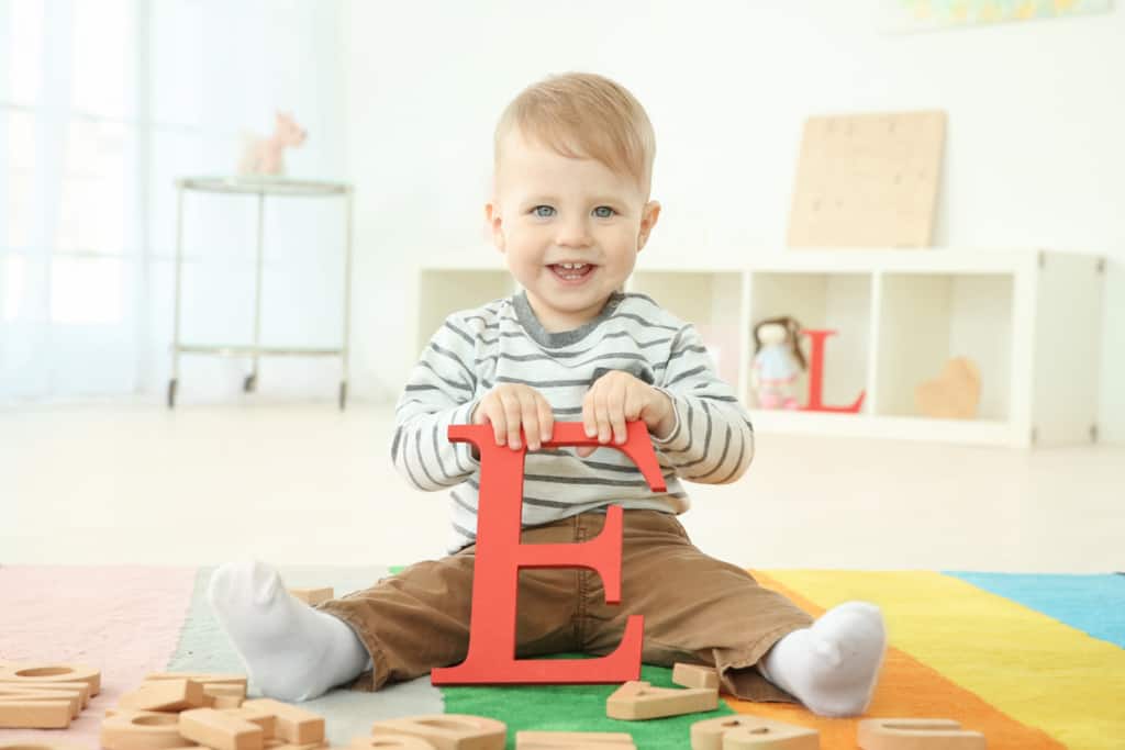 Boy holds wooden letter "E" for his single syllable boy name.