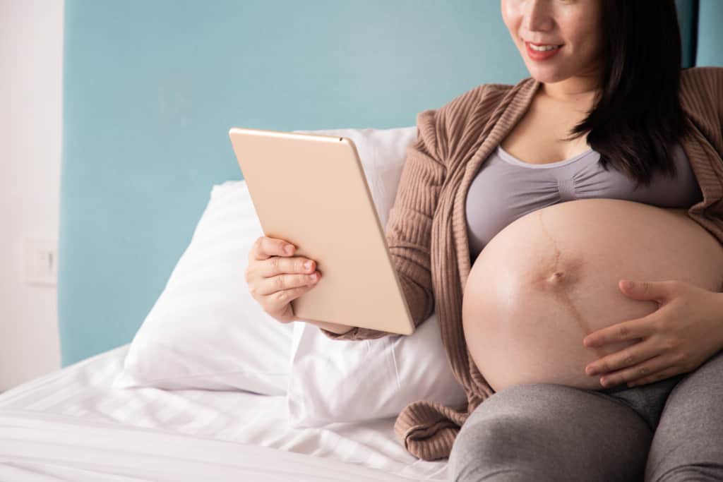 Pregnant woman searches for one syllable boy names on tablet device.