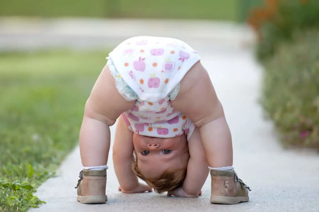 Cute baby girl plays on sidewalk.
