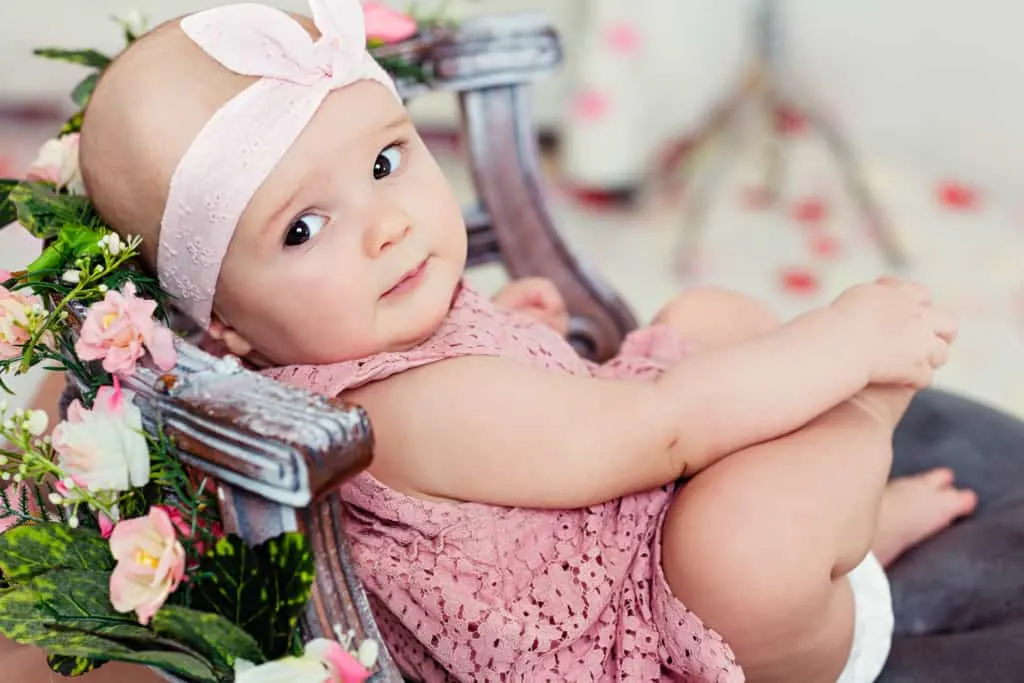 Baby girl reclines in flower covered chair.