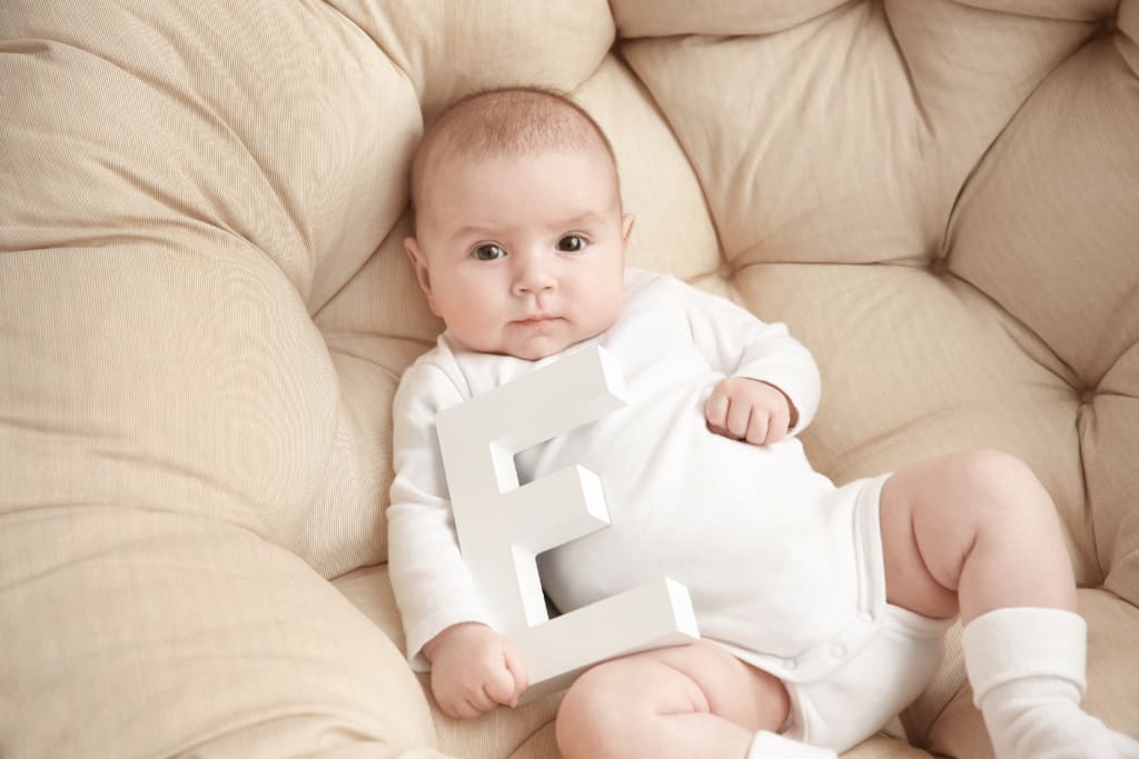 Baby boy holding letter "E" for name.