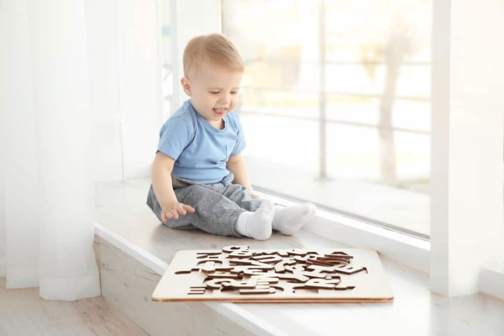 Bébé garçon joue avec un puzzle de lettres en bois.