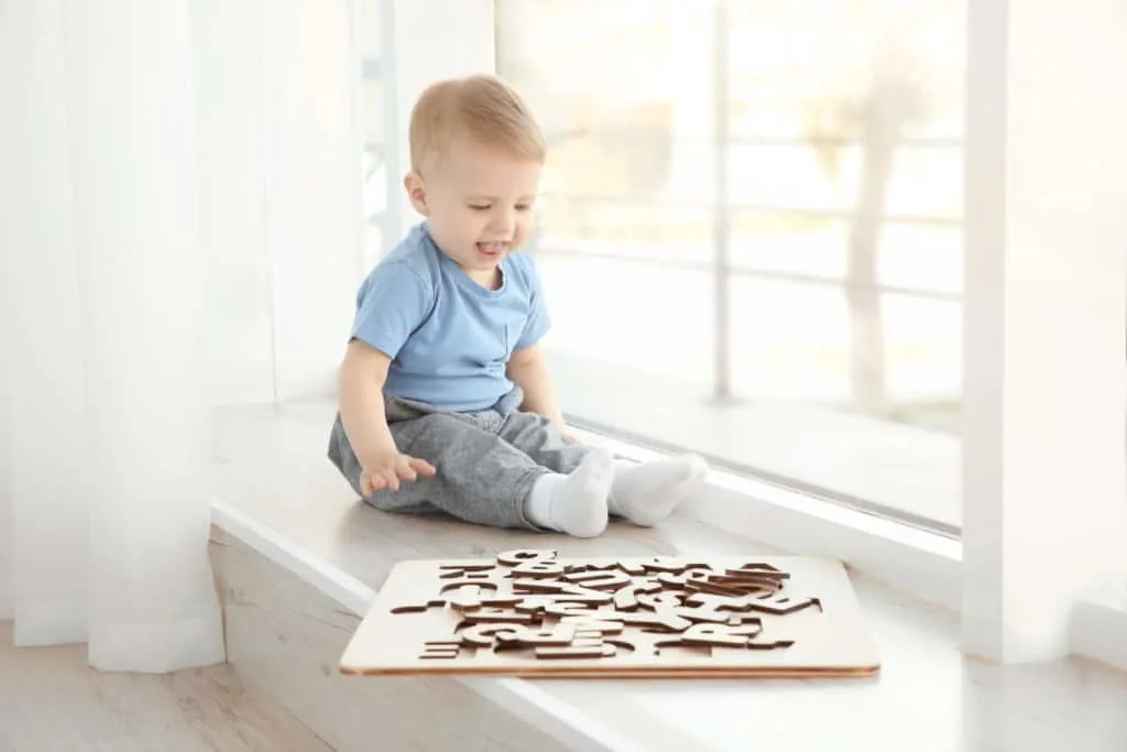 Baby boy plays with wooden letter puzzle.