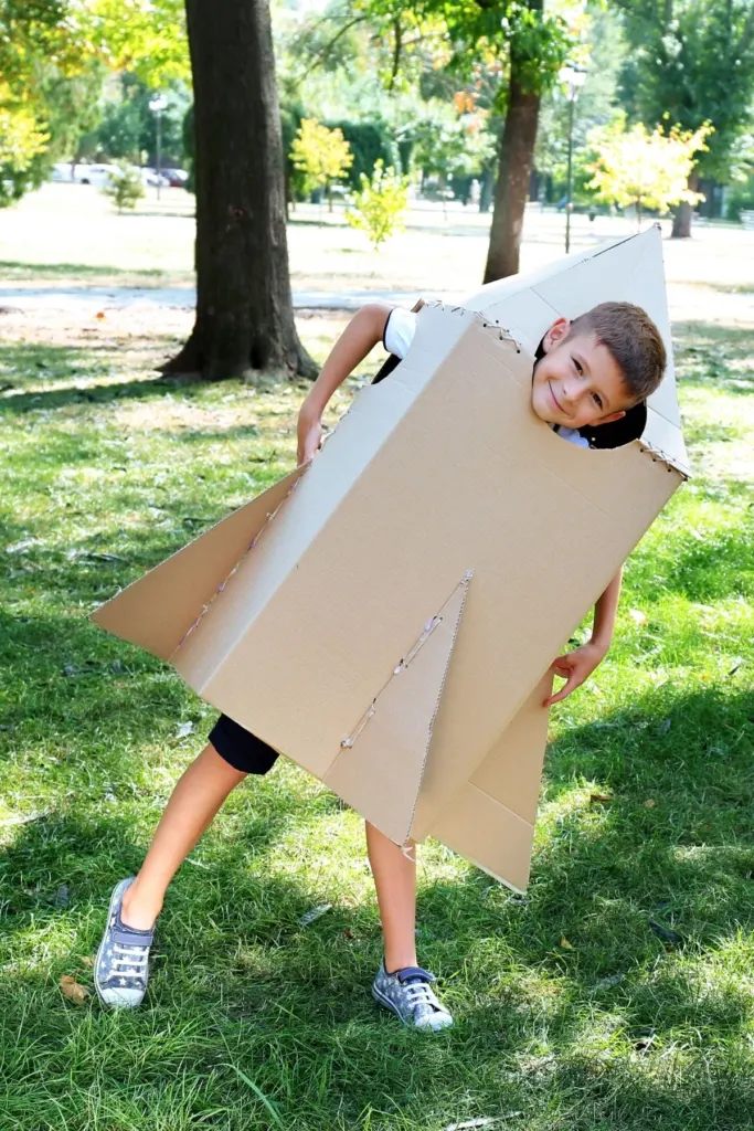 A a boy in a rocket costume made out of cardboard.