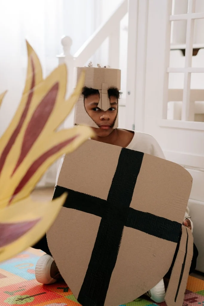 A boy in a knight costume made out of cardboard.
