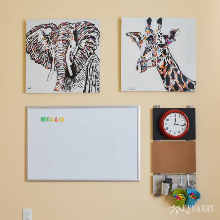 DIY playroom wall decor gallery with elephant and giraffe art, a dray erase board, a clock and craft storage.