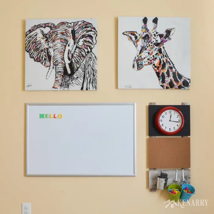 DIY playroom wall decor gallery with elephant and giraffe art, a dray erase board, a clock and craft storage.