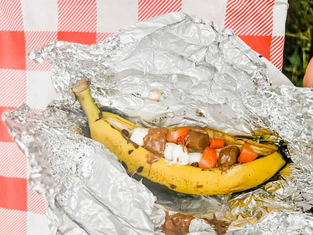 A campfire banana boat with chocolate, marshmallows, and strawberries in tinfoil.
