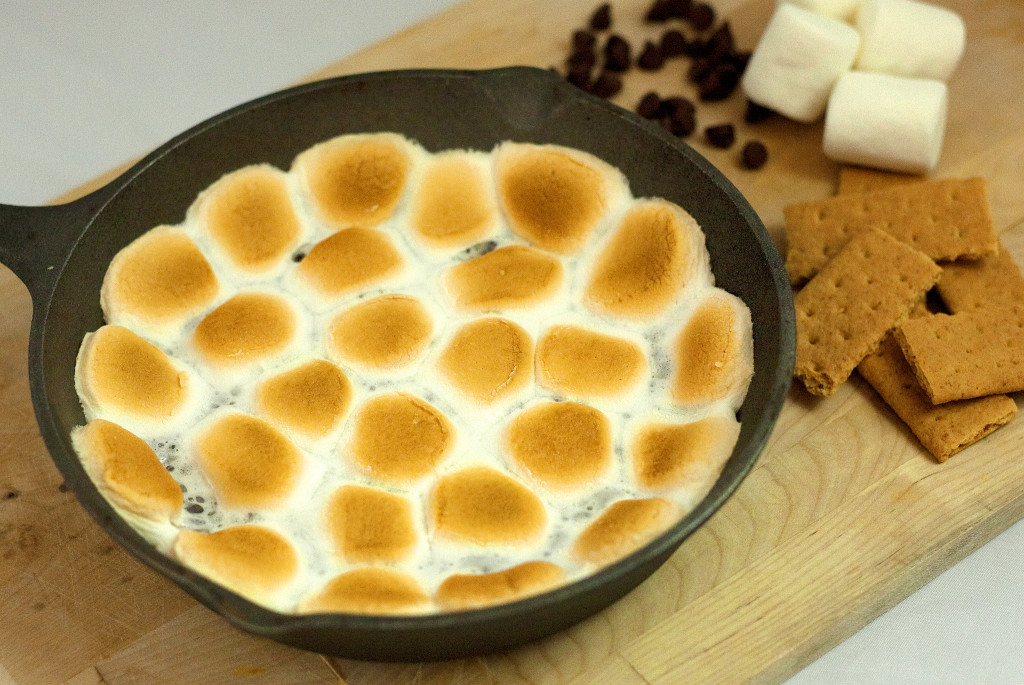 Smores dip in a cast iron skillet next to ingredients.