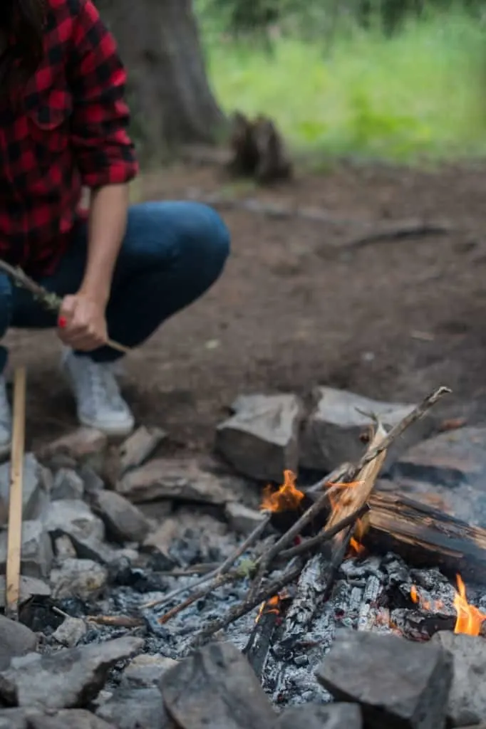 person near campfire starting the fire