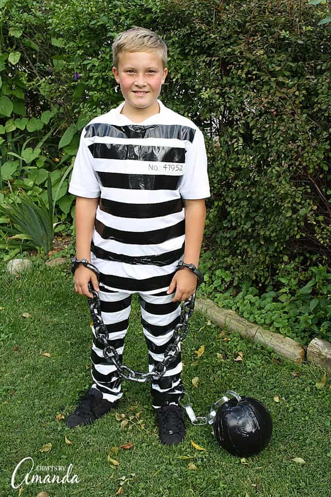 A boy dressed in black and white striped, DIY Prison clothes with a ball and chain around an ankle.