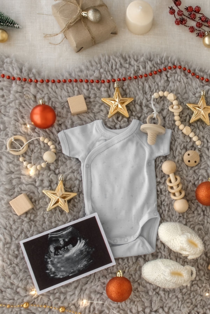 An ultrasound photo next to a onesie and Christmas ornaments.