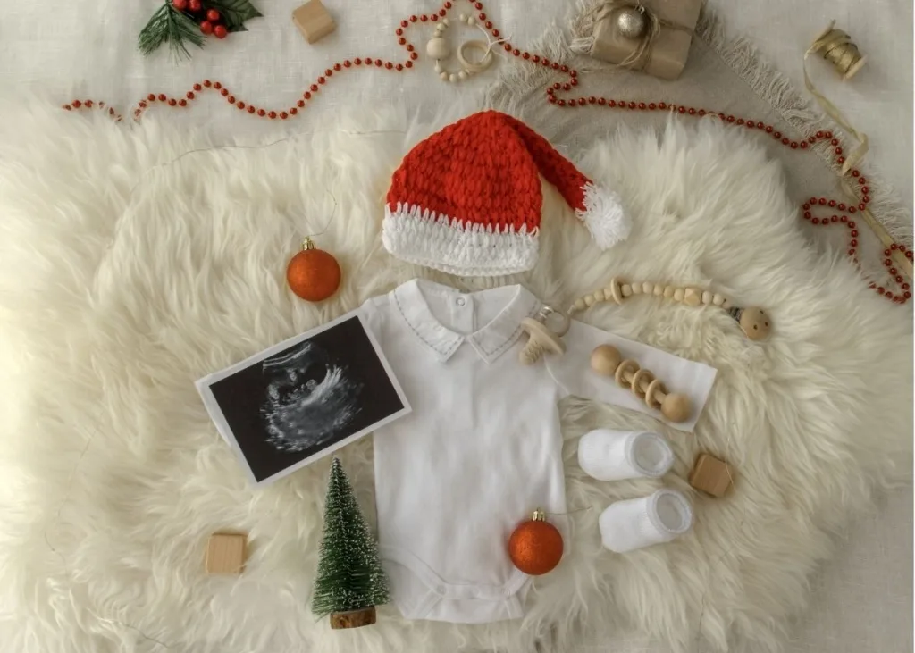 Christmas flat lay baby announcement with a onesie, Santa hat, and an ultrasound.