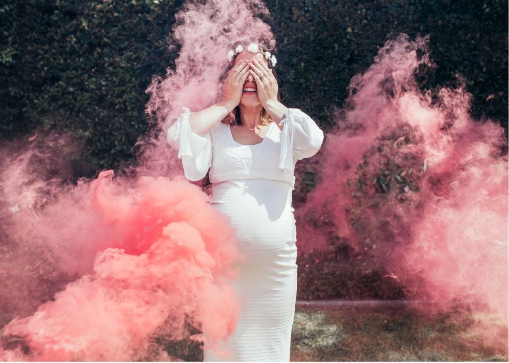 A woman in a white dress surrounded by pink smoke.