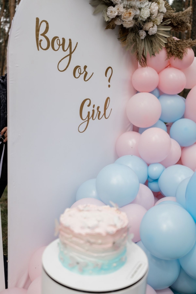 A sign that says "boy or girl" next to pink and blue balloons.