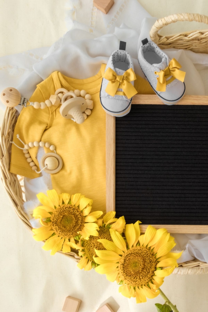 Sunflowers with a yellow baby onesie and a letterboard sign.