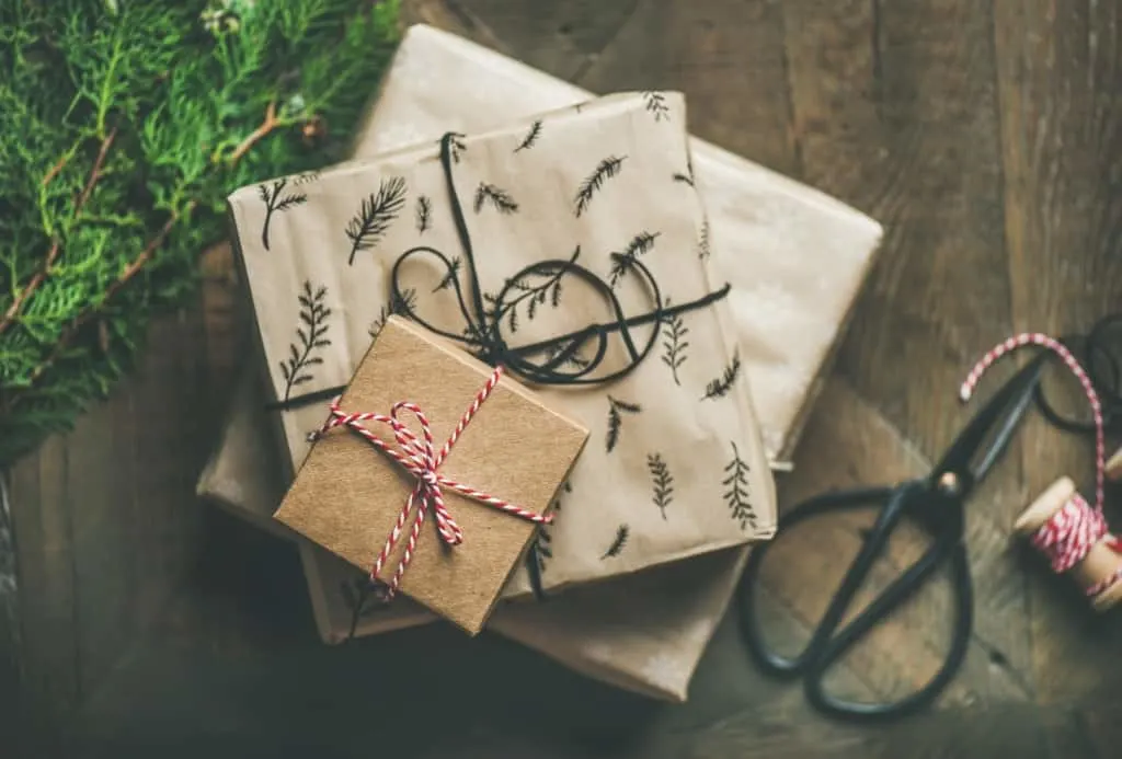 Stacked Christmas gifts by tree.