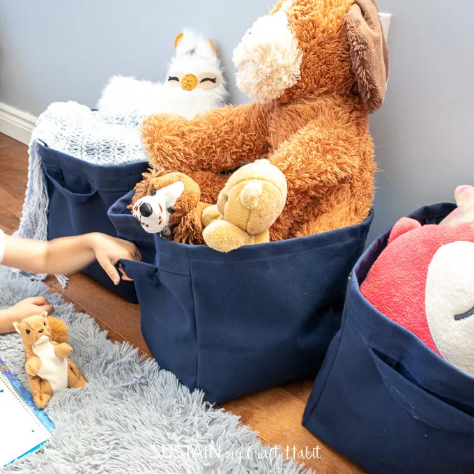 Homemade canvas storage totes with stuffed animals inside.