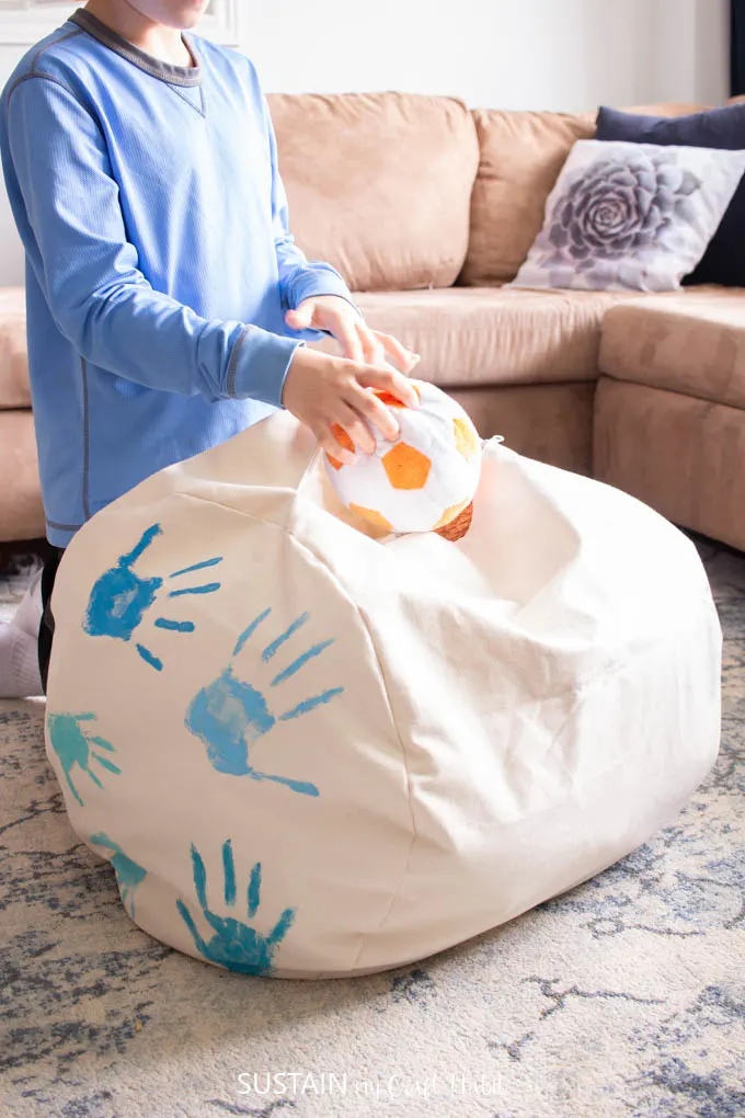 A homemade toy storage ottoman with painted handprints as decorations.
