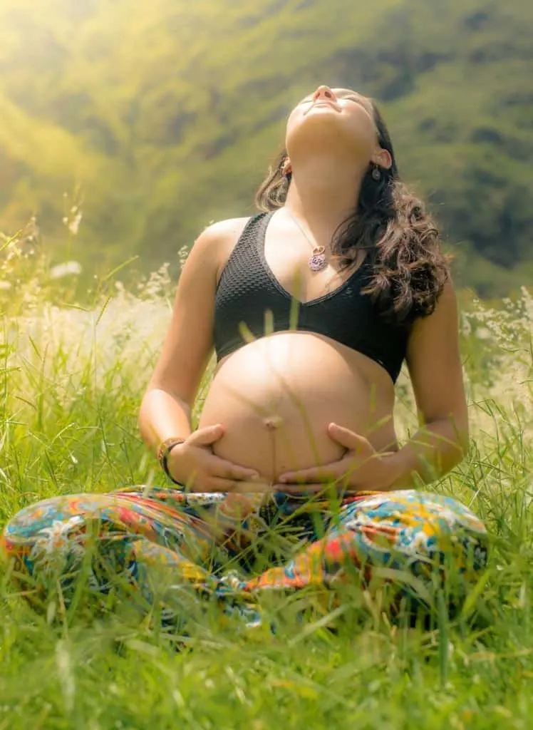 Bohemian pregnant woman poses in field and thinks of hippie names for boys and girls.