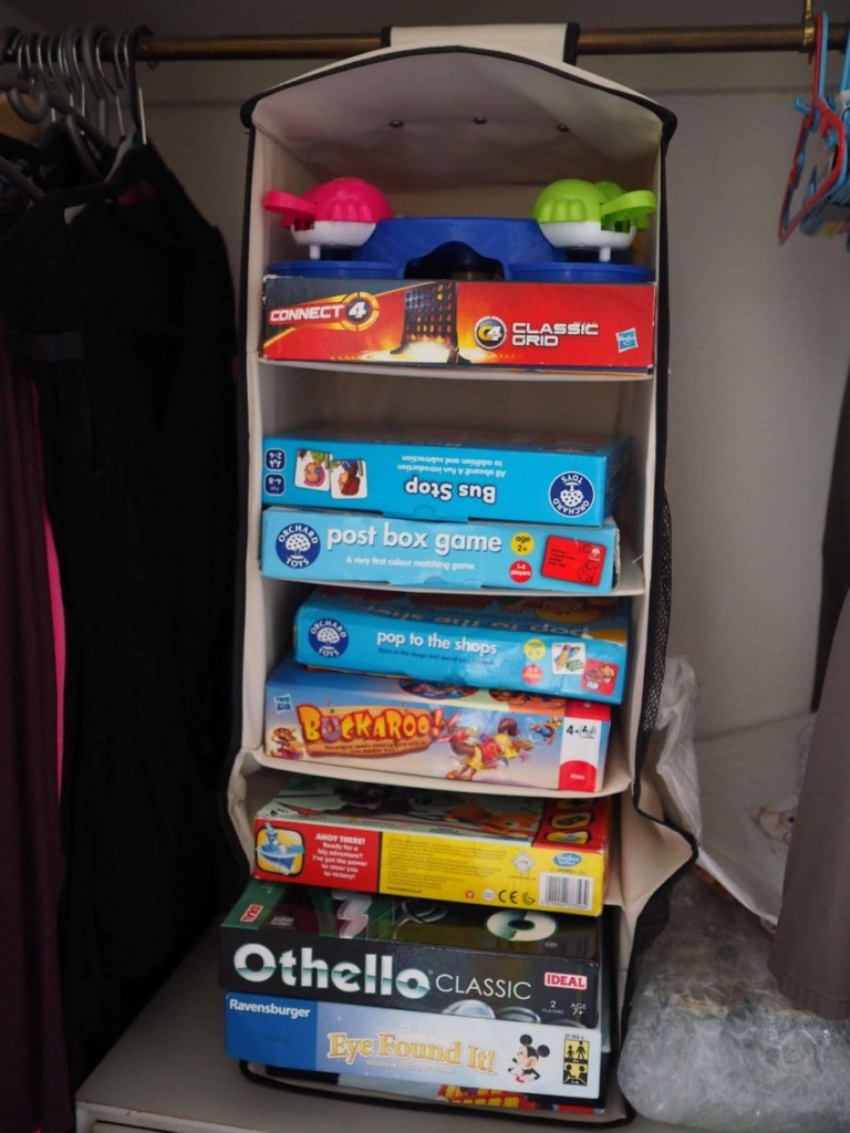 A hanging board game organizer in a closet.