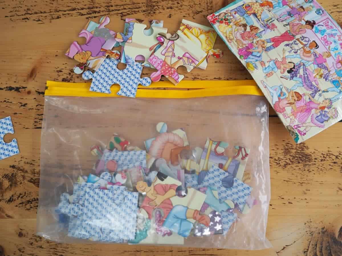 Clear plastic baggie with puzzle pieces inside on the floor.