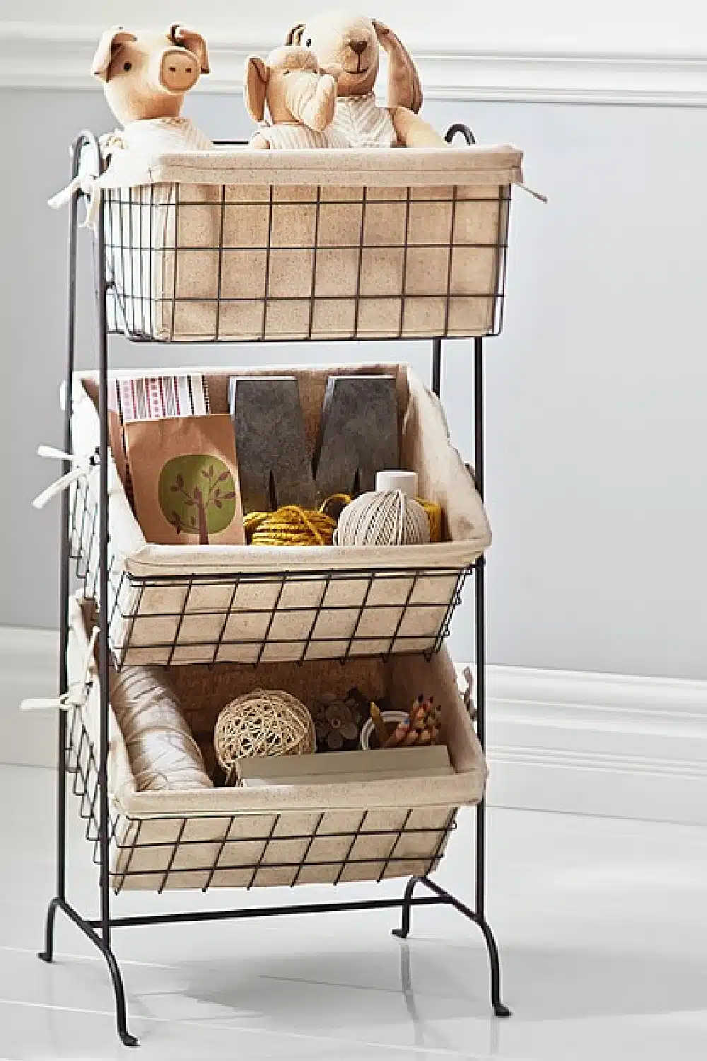 Wire baskets with toys inside hanging in a stand.