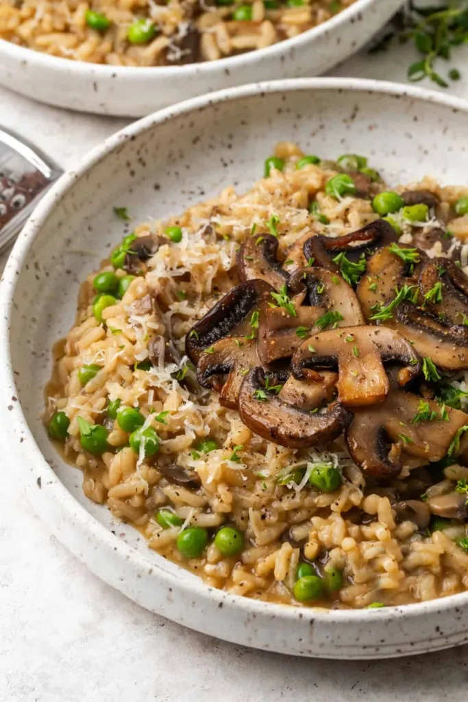 Mushroom risotto with peas and finely shredded white cheese on top.