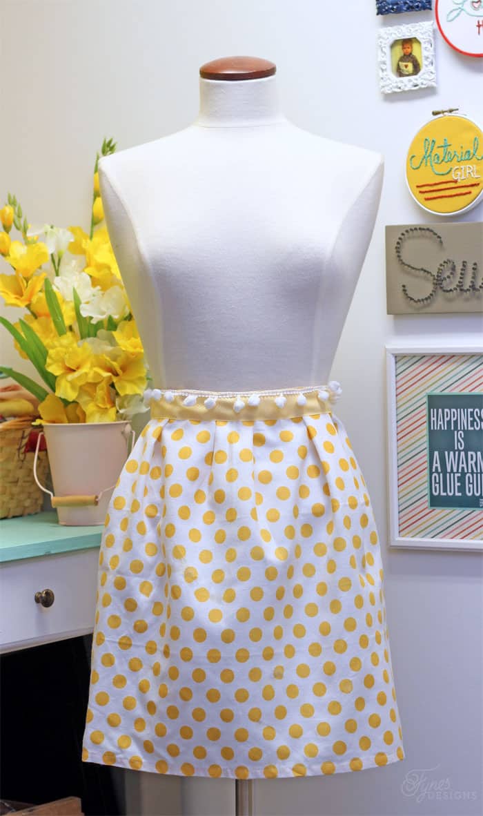 Yellow polka dot tea towel apron on a white manequin.