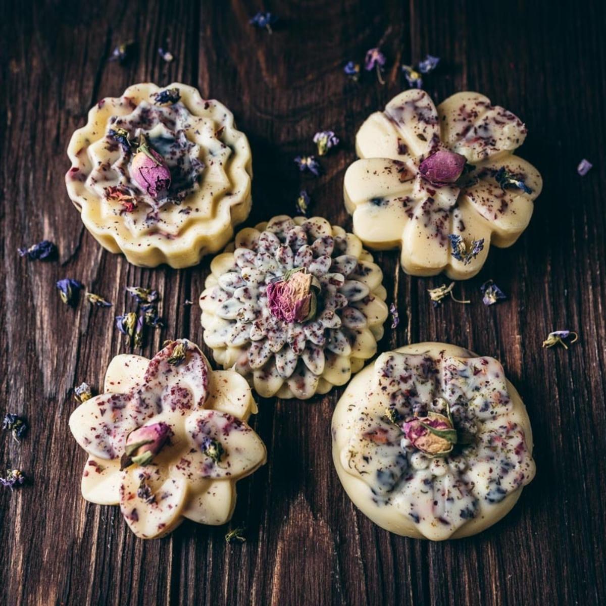 Homemade lotion bars with flowers on a wood background.