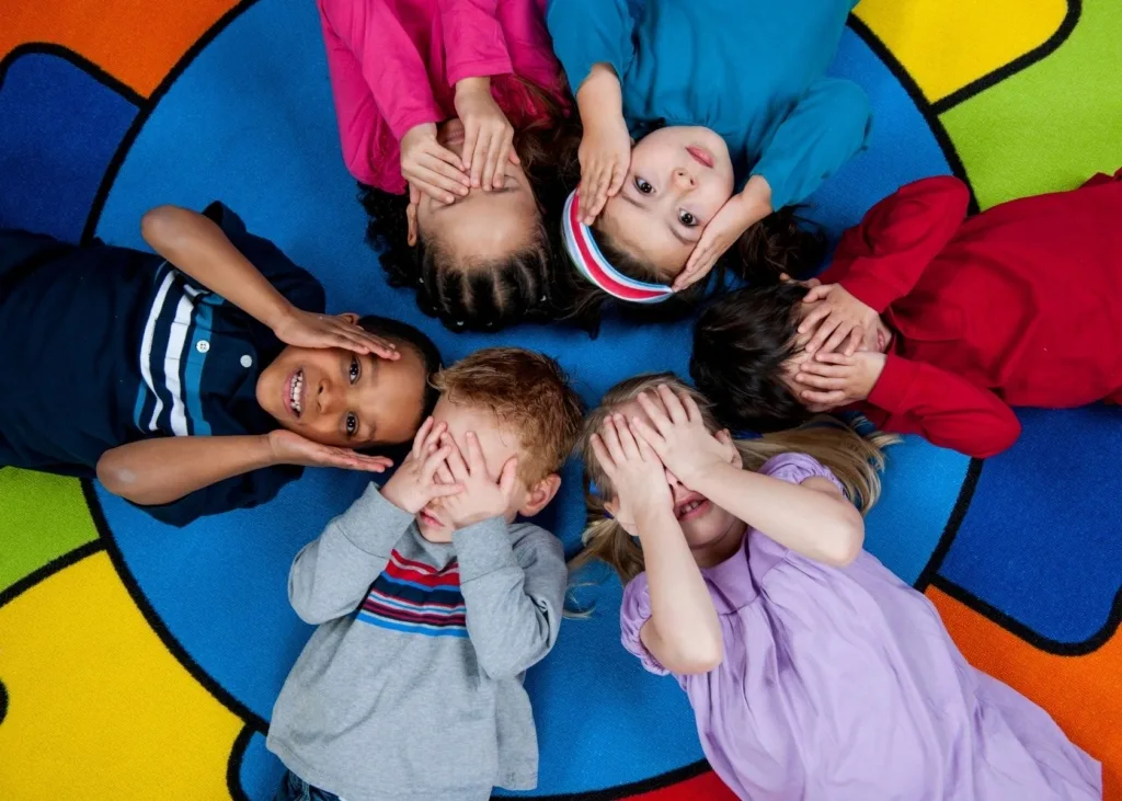 Children play a game and cover their faces in a circle.