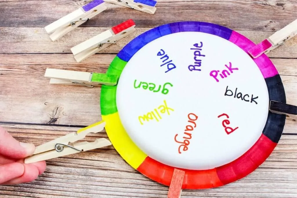 A paper plate with the colors of the rainbow around the rim and matching clothespins.