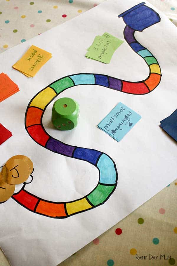 A homemade rainbow board game for kids with cards and gold coins.