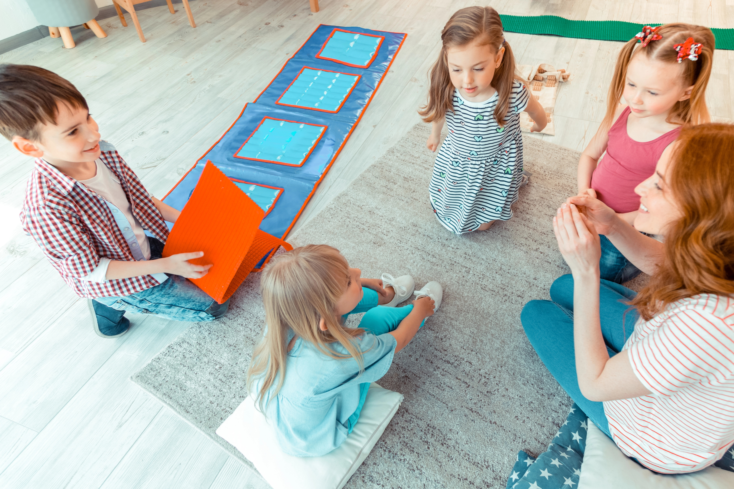 Preschool kids sitting in a circle with their teacher doing an activity.