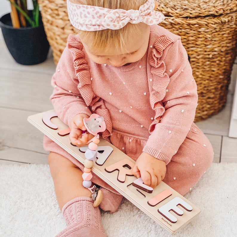 1 year old girl playing with a name puzzle.