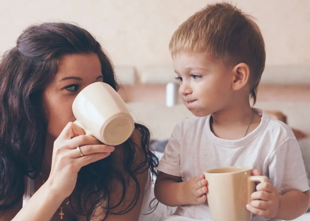 Mom and toddler drink from mugs.