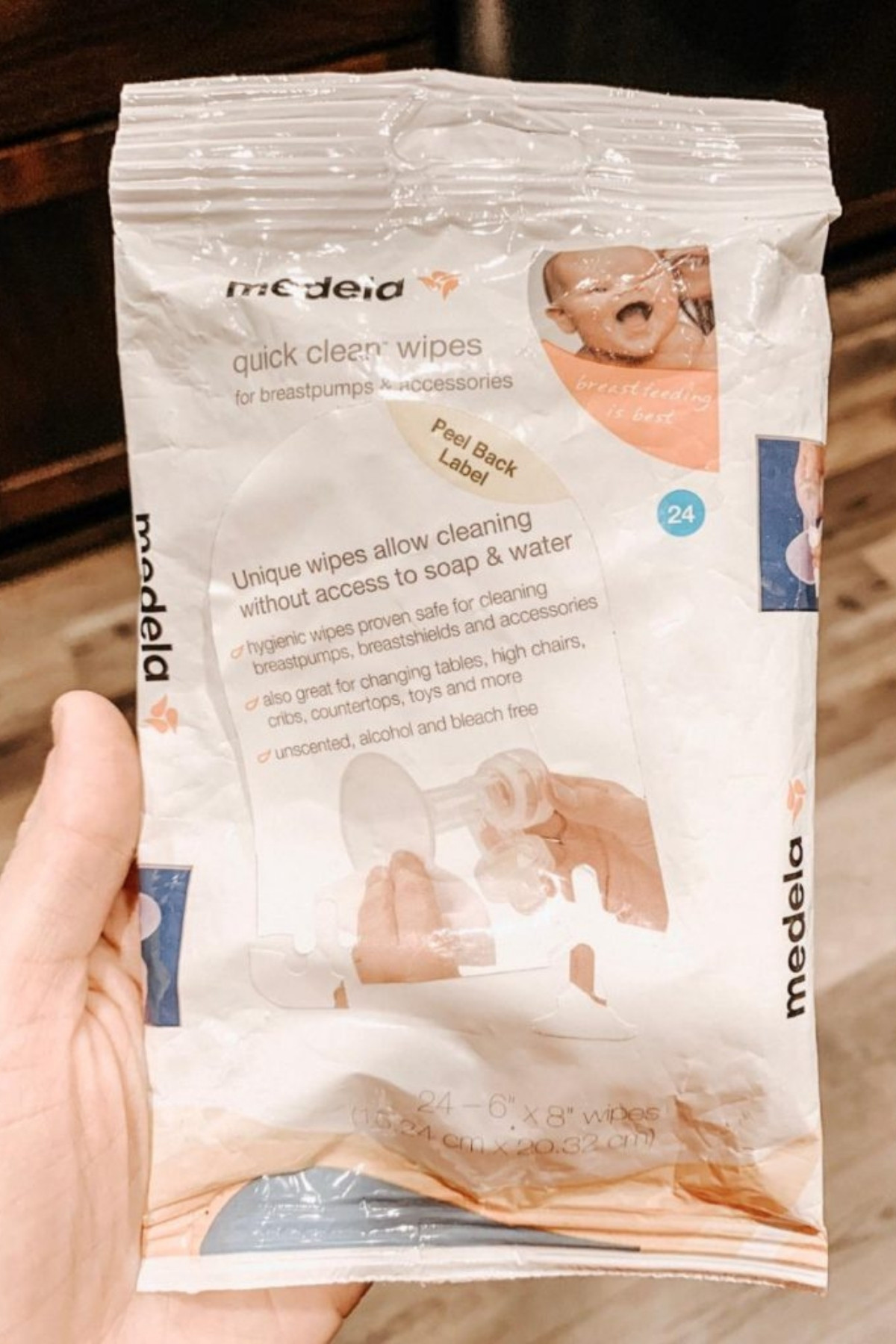 Woman holds up package of Medela on-the-go breast pump cleaning wipes.