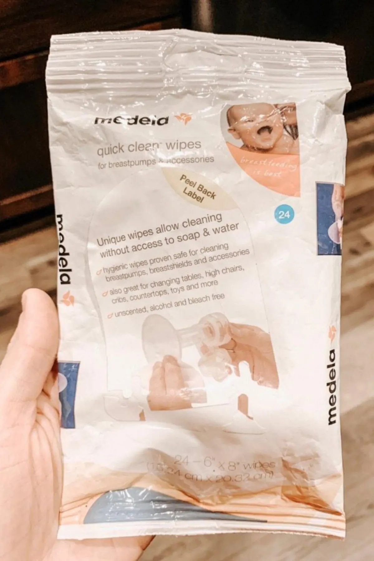 Woman holds up package of Medela on-the-go breast pump cleaning wipes.