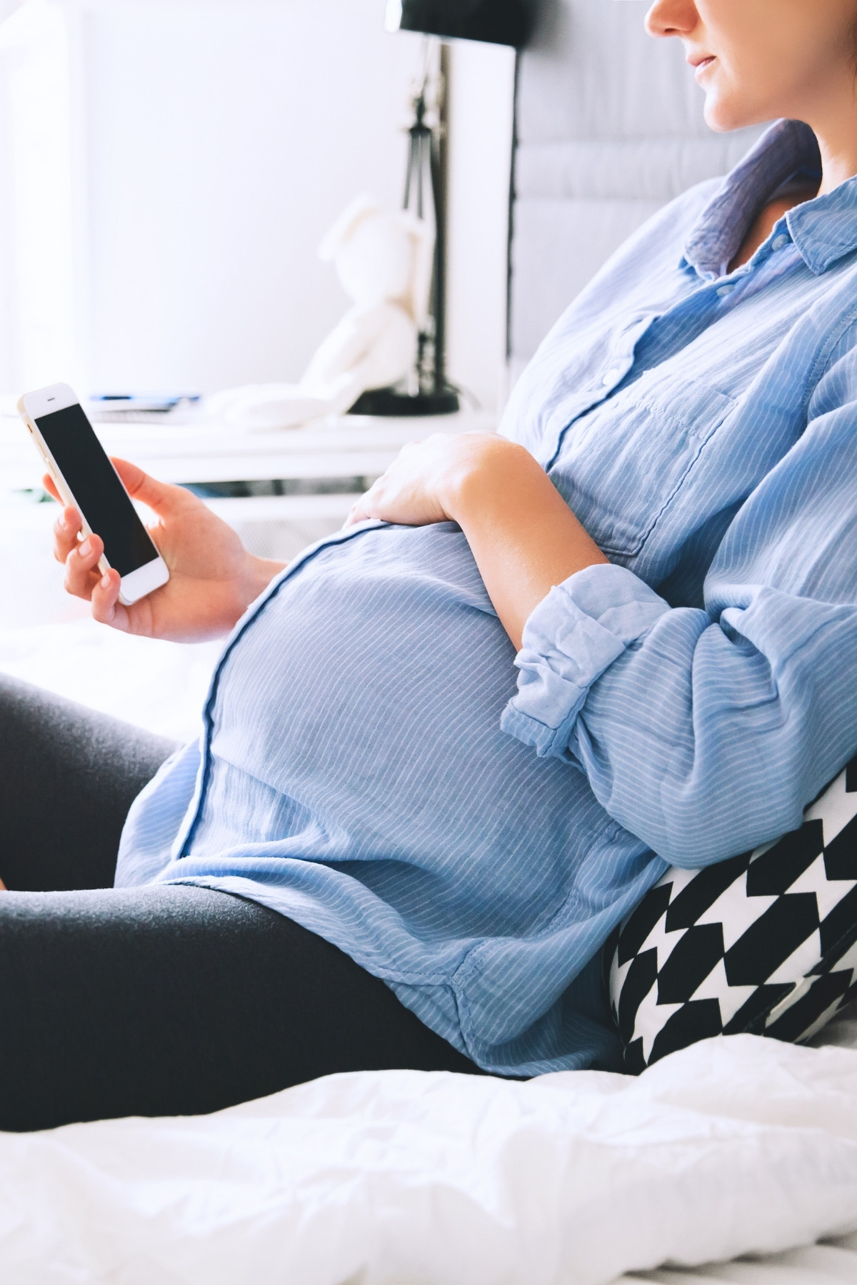 Pregnant woman types essential questions to ask at your 1st prenatal appointment into her phone.