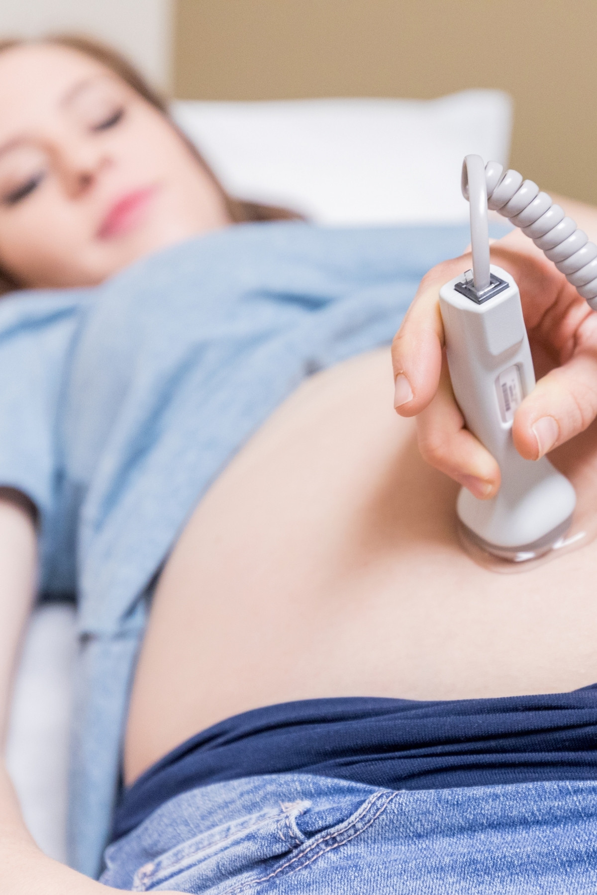 Pregnant woman lies on the bed in a doctor’s office while receiving a pregnancy ultrasound.