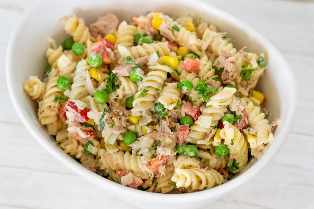 Tuna pasta salad with peas and corn in a white bowl.