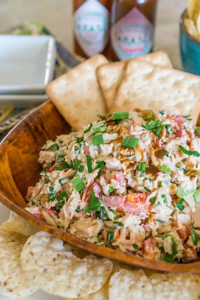 Spicy chicken salad in a wooden bowl with crackers.