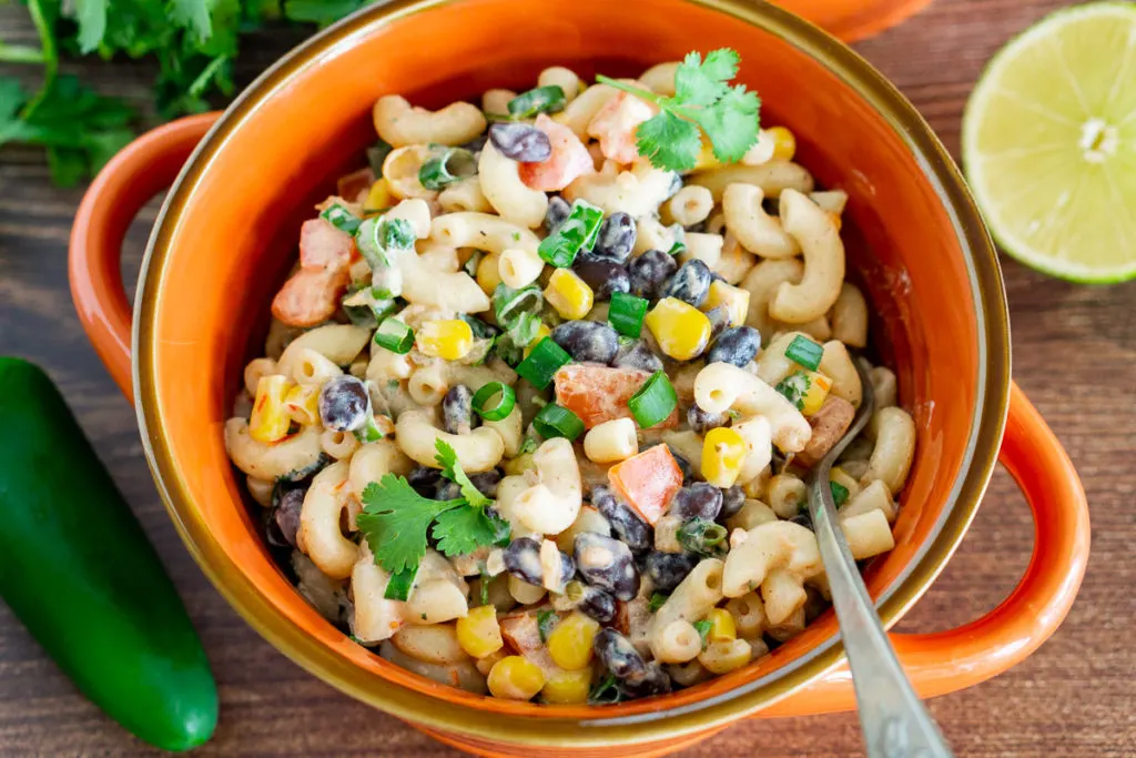 Mexican pasta salad with black beans and corn in a clay bowl.