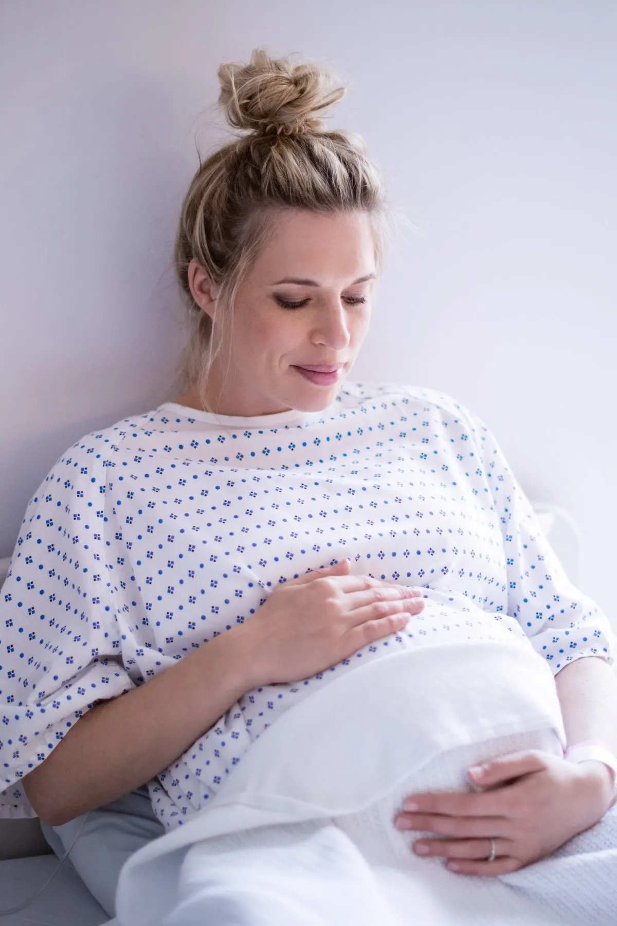 Pregnant woman sits up in hospital bed as she prepares for labor.