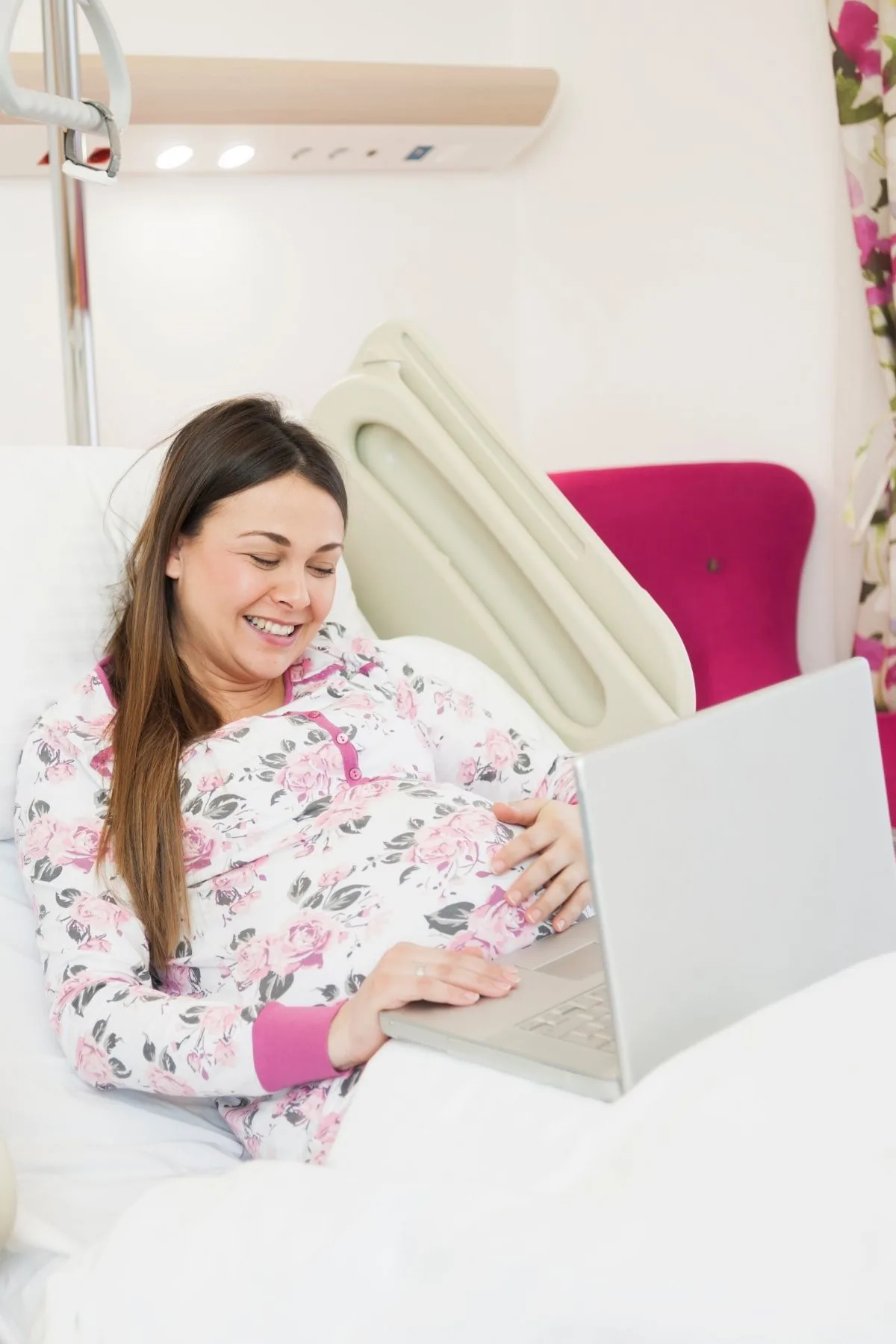 Pregnant woman in hospital bed uses her laptop computer for distraction during labor.