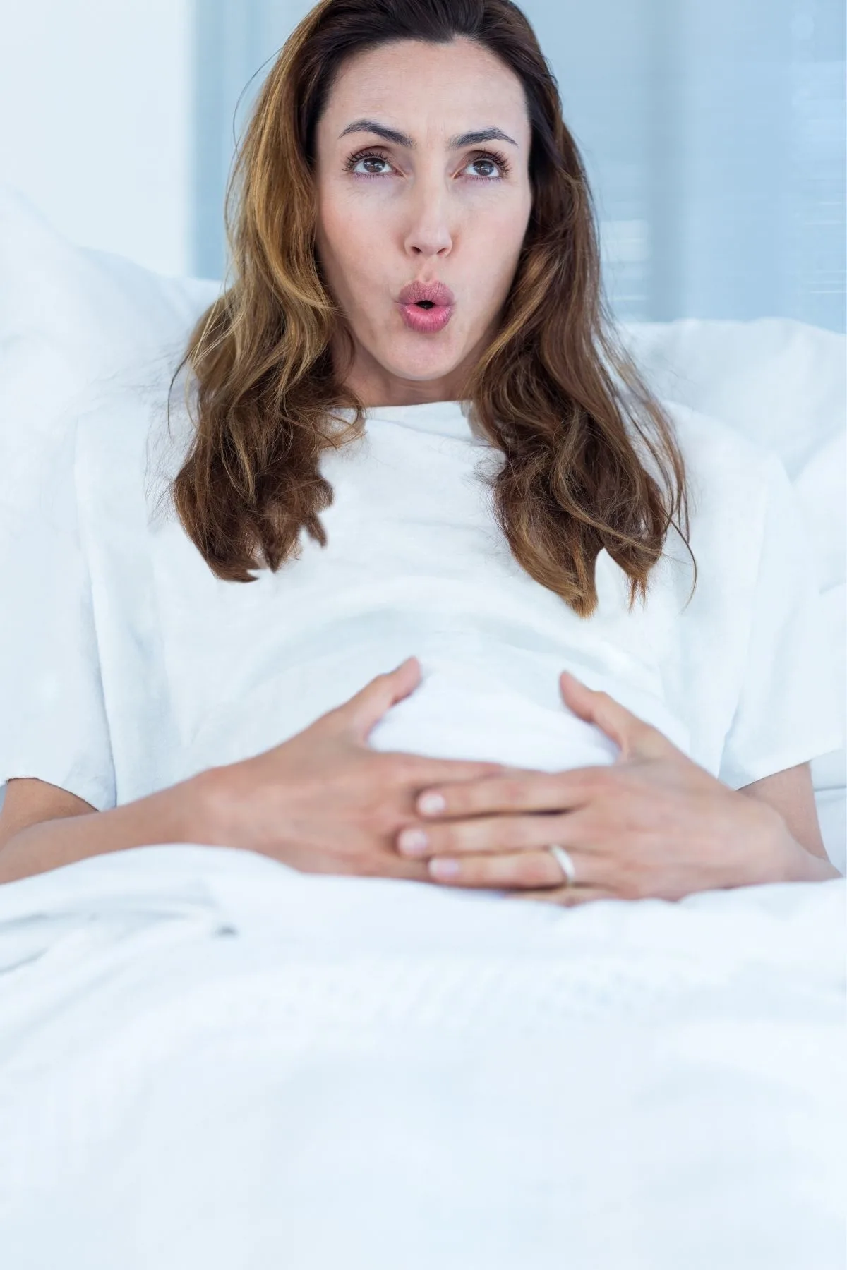 Woman in hospital bed uses rhythmical breathing to ease painful contractions during labor