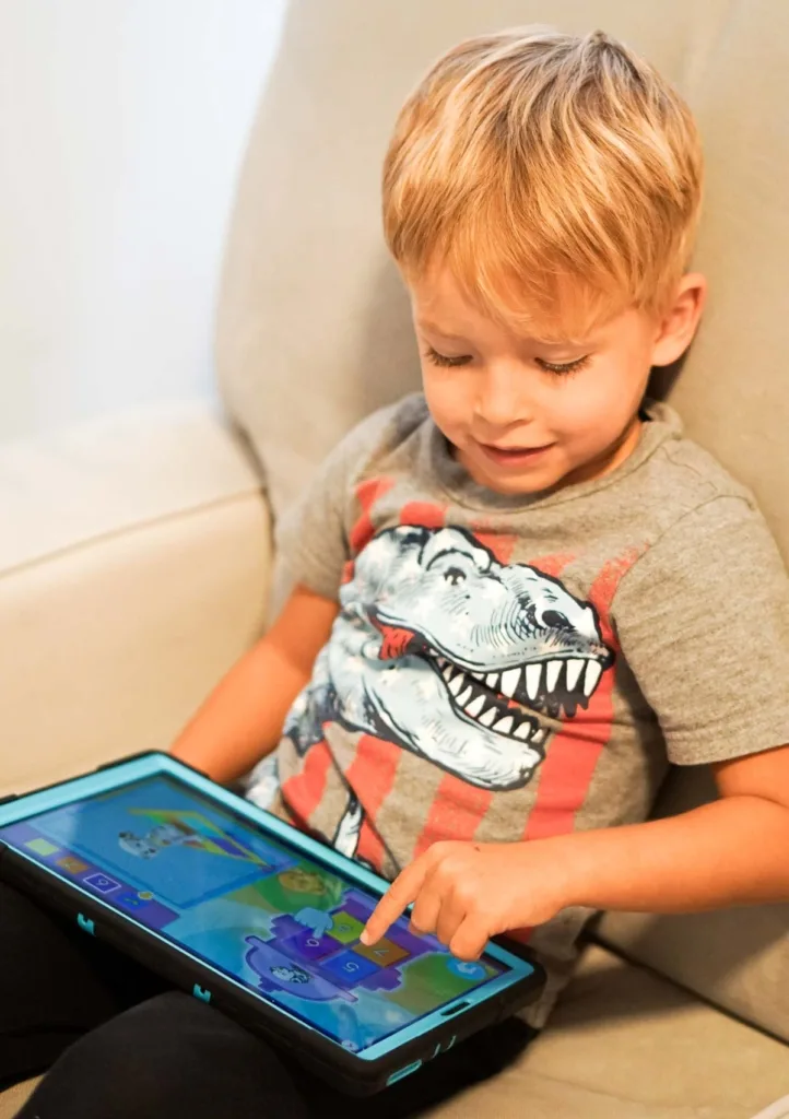 Toddler playing math game on tablet while sitting in an armchair.