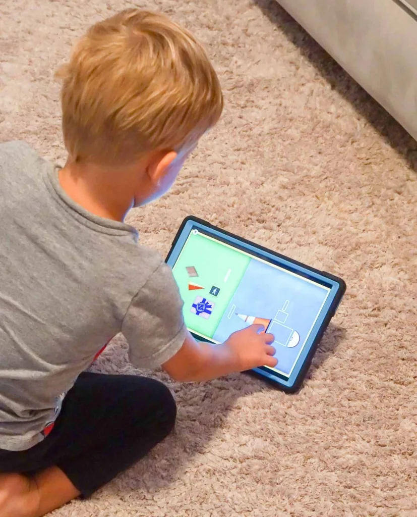 Toddler playing shape game on a tablet.